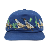 Blue hat embroidered with a desert scene of quails crossing among cacti