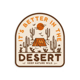 Desert camping sticker featuring a tent among tall cacti under an orange sun with the phrase It's Better In The Desert Keep Nature Wild
