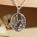 Sterling silver hummingbird pendant with flowers inside a circular frame on a silver chain necklace