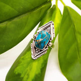 Silver ring with a turquoise stone and copper veining set in a bold geometric frame.