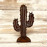 Spiky rusty metal cutout of a saguaro cactus with several arms and white ridge lines on a rounded base