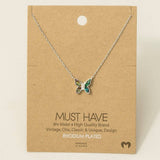 Gold dipped butterfly pendant necklace with white enamel wings on a slim chain