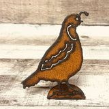 Rusty metal quail cutout standee on a small base against a weathered wood background
