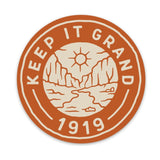Round orange Keep It Grand 1919 sticker with a desert canyon scene in cream