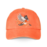 Orange washed dad hat with an embroidered American kestrel in flight on the front
