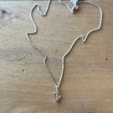 Gold and silver dainty cactus pendant necklaces laid on a wooden surface