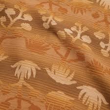 Close up of Sheridan Flannel fabric in Maguey Mirage showing tan and orange tropical leaf pattern.