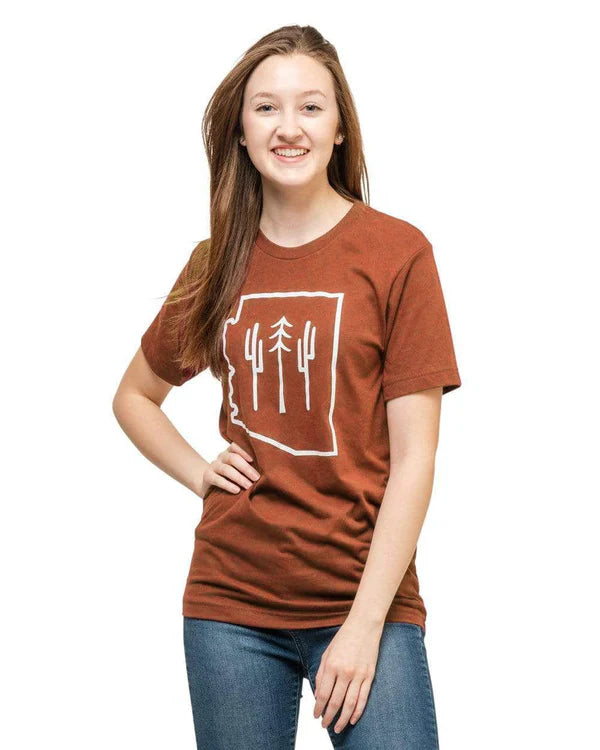 Smiling model wearing the Redwood AZ Wilderness Tee with white desert line art and blue jeans
