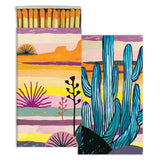 Blue Saguaro Matches set in a two panel desert artwork with tall blue cacti and sunset colors.