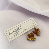 Mini copper saguaro cactus dangle earrings with gold hook wires and textured gold accents.