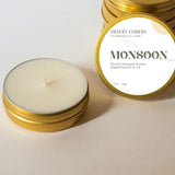 Monsoon 1.7 oz travel candle in a gold tin with a white label