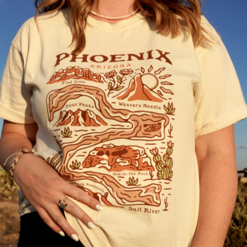 Beige Phoenix Arizona Landmark Tee worn by a woman, showcasing a stylized desert map across the front