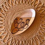 Oval prickly pear ceramic tray with a cactus illustration set on a woven circular jute placemat