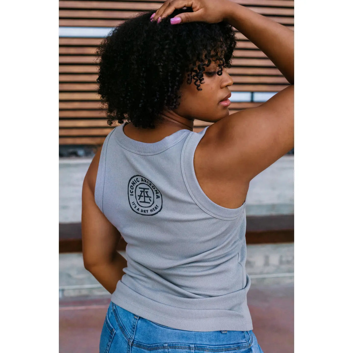 Back view of light gray Skull Mountain Organic Rib Tank with circular logo on the back, worn with blue jeans.