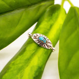Silver turquoise eye ring with an oval stone set in a radiating sunburst frame on a textured band.