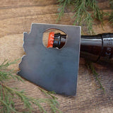 Arizona state silhouette bottle opener mounted on a dark plate with a bottle nearby on a wooden surface.