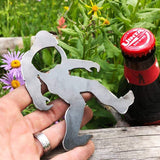 Metal Bigfoot Yeti bottle opener held in a hand with a beer bottle nearby