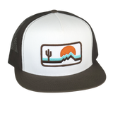 Retrozona flat brim trucker hat with white front panel and brown brim featuring an embroidered desert landscape patch with cactus mountains and a sun