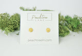 Small gold daisy stud earrings on a white display card