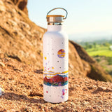 Arizona Camelback Moon insulated steel water bottle with a colorful desert landscape on white, placed on a rocky trail