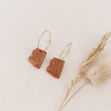 Terracotta square geometric charms on slim gold hoop earrings.