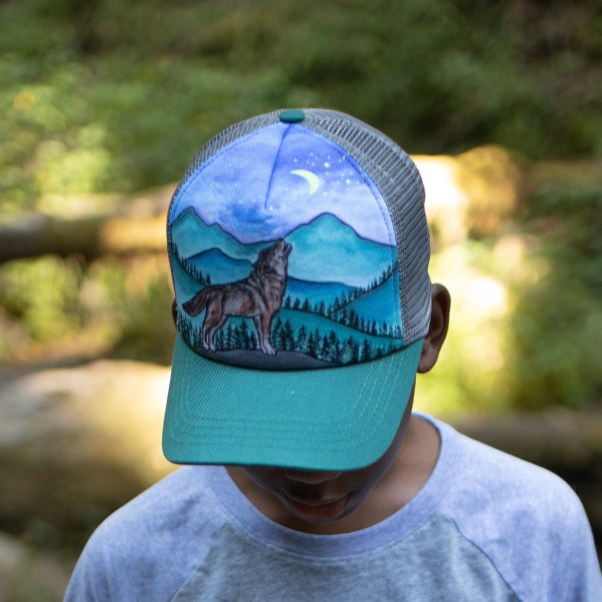 Kids Lone Wolf Trucker Hat with a wolf and mountain scene on a blue front panel and green mesh
